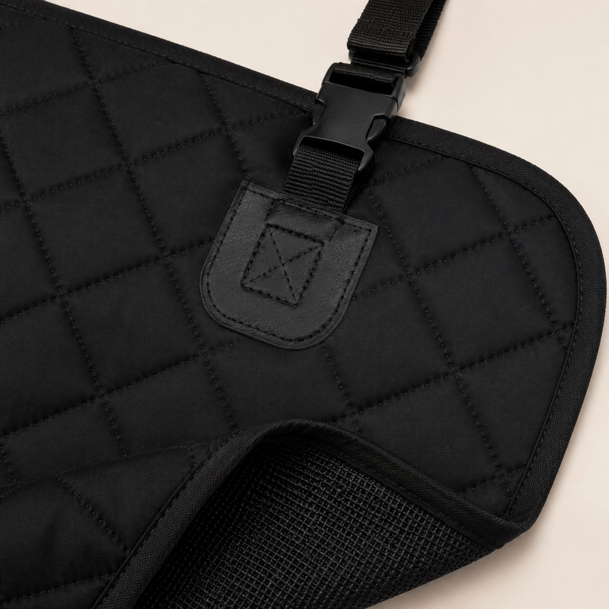 Close-up of rear-seat protector quilting, bound edge, strap anchor and buckle
